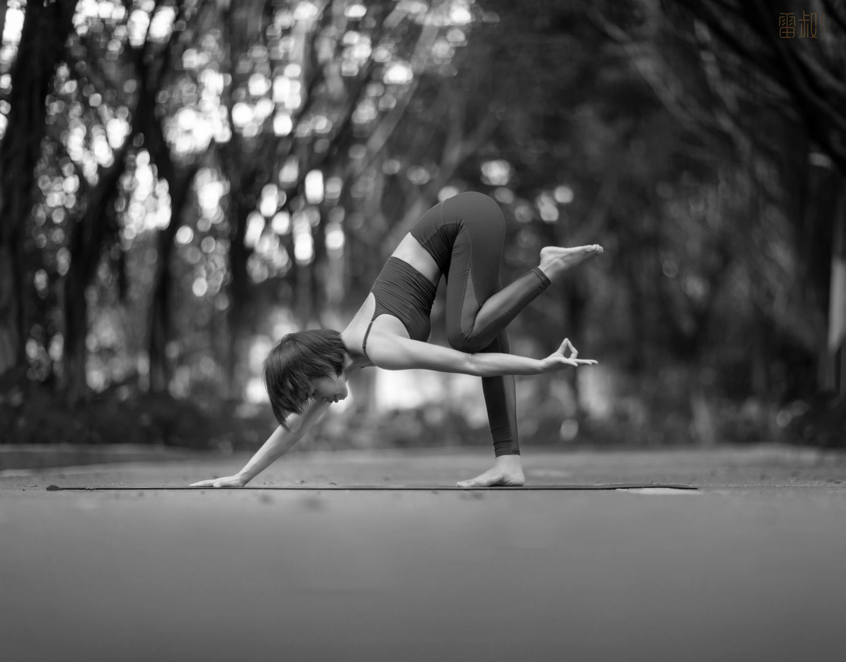 A woman practicing yoga in a park, captured in black and white. (Photo by RAY LEI on Pexels)