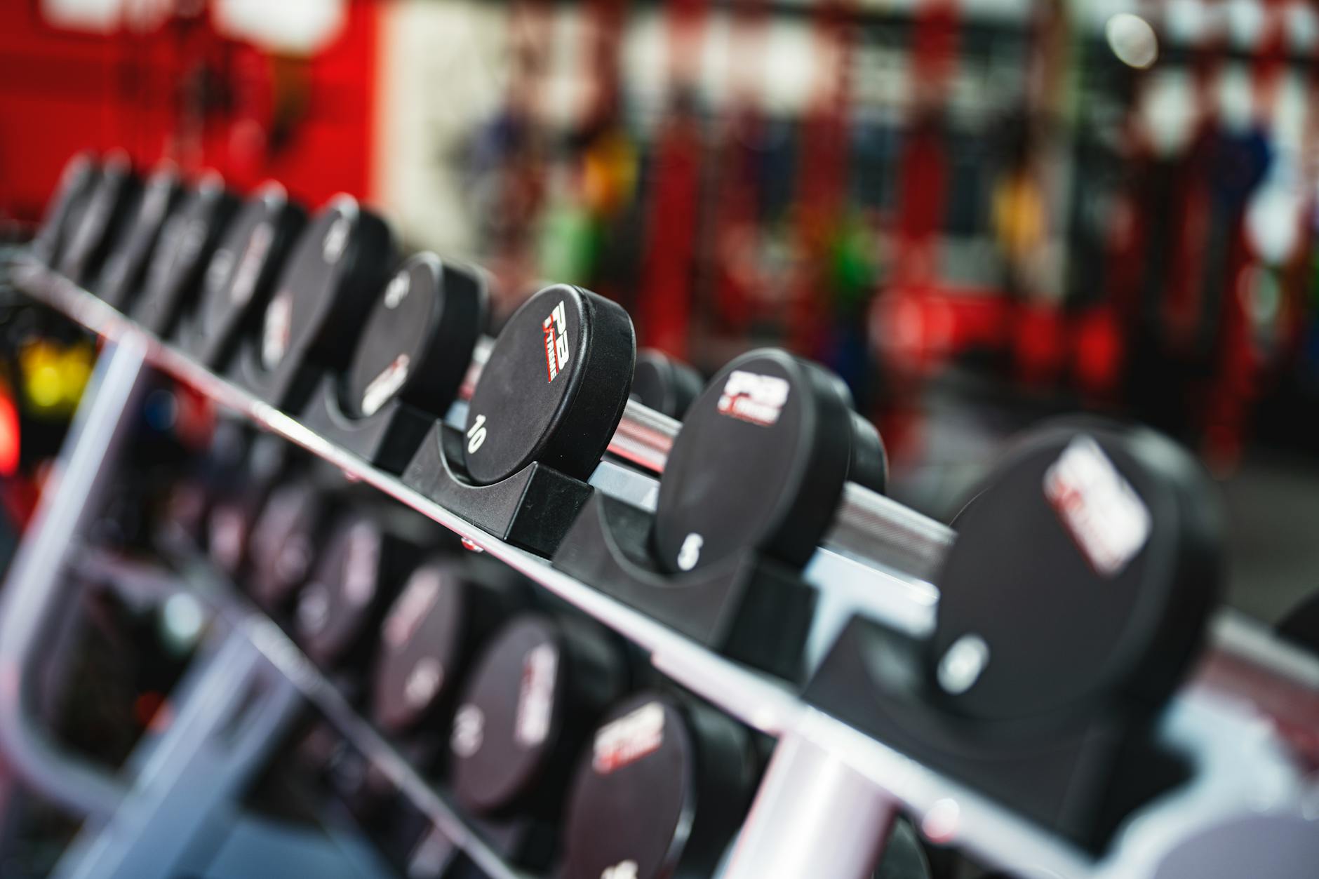 Close-up view of dumbbells in a modern gym setting, emphasizing fitness and training. (Photo by Jason Morrison on Pexels)