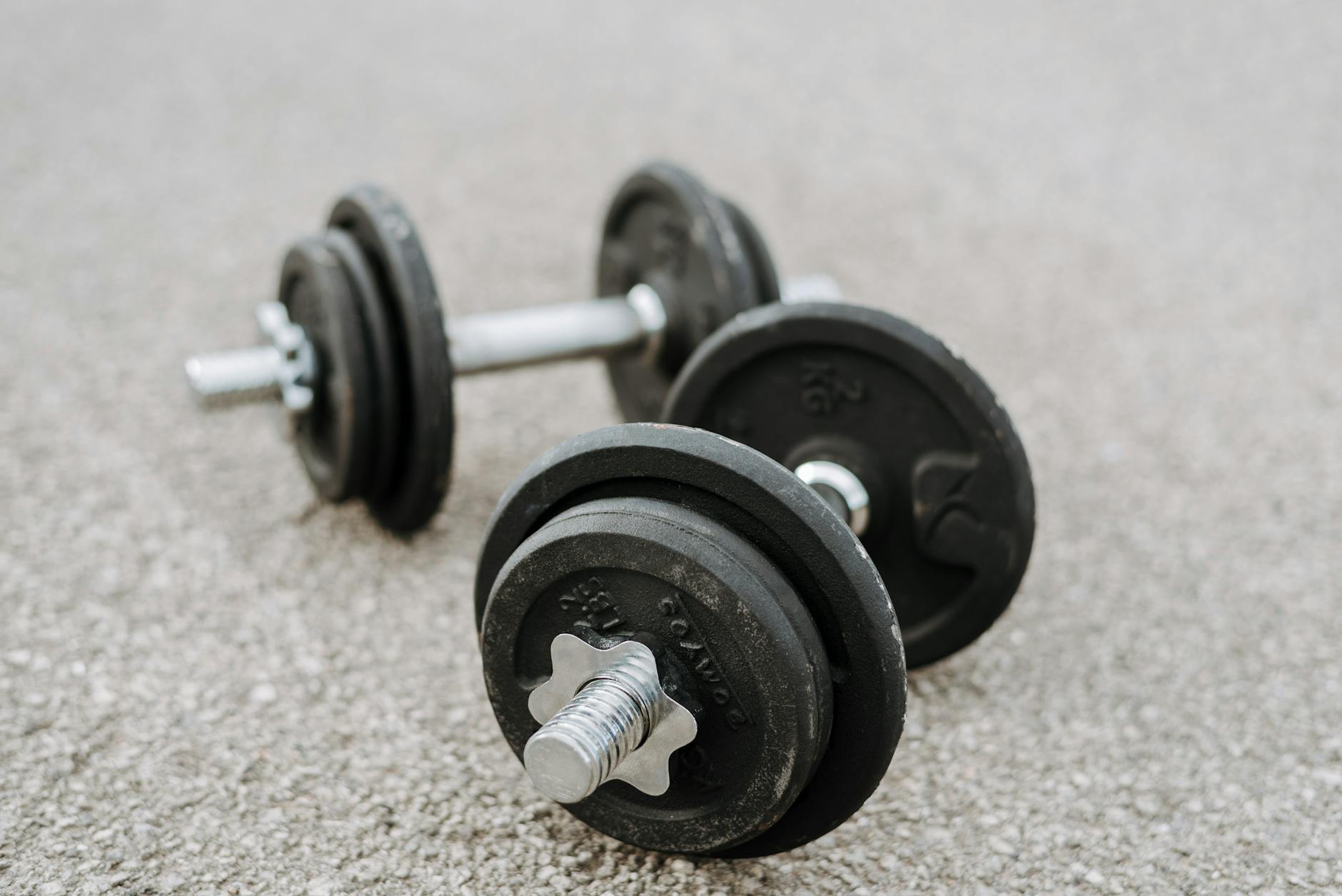 Massive metal dumbbells prepared for difficult healthy training on asphalt road in summer (Photo by Anete Lusina on Pexels)