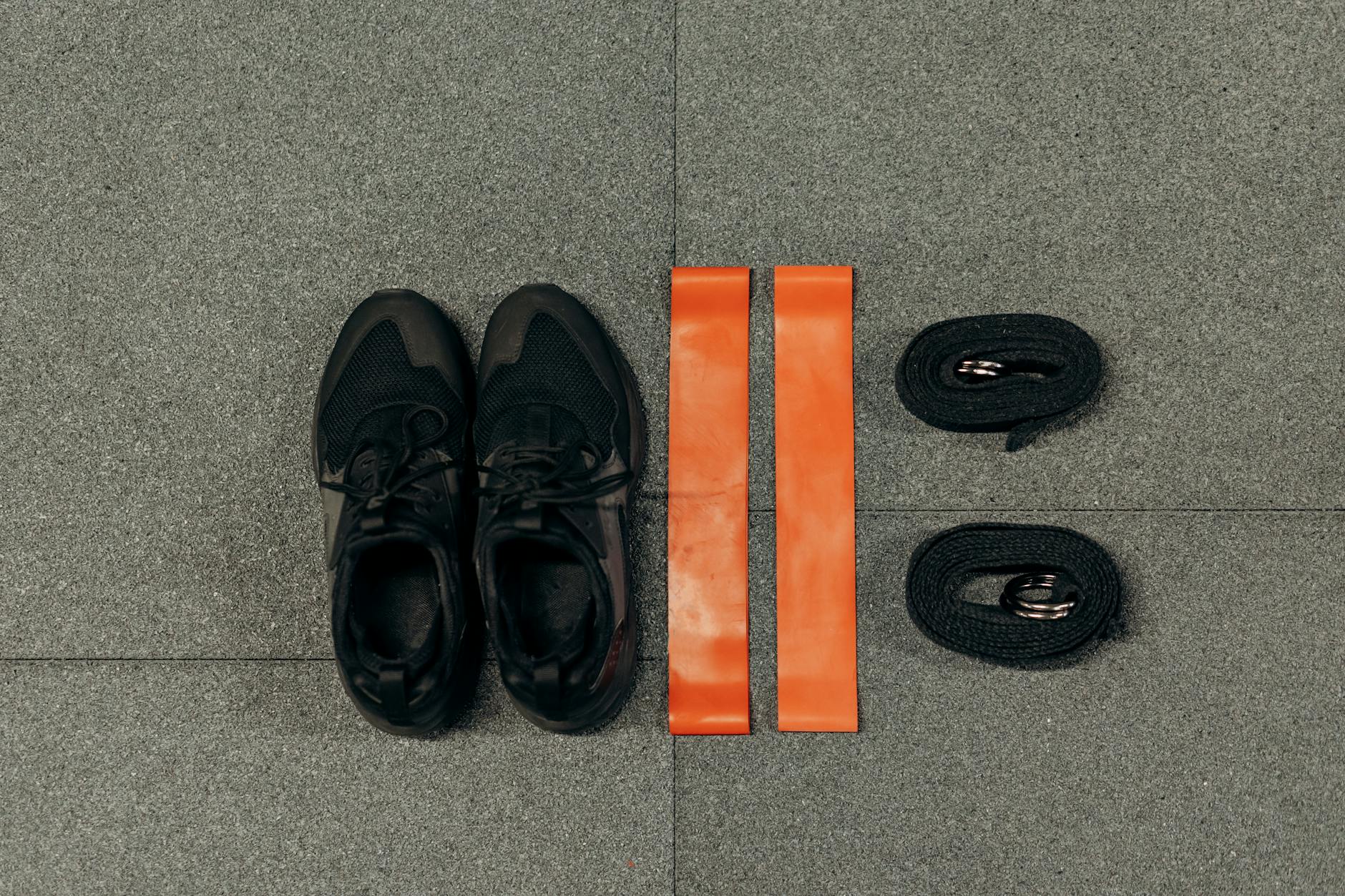 Flat lay of fitness essentials: sneakers, resistance bands, and straps for training. (Photo by Mikhail Nilov on Pexels)