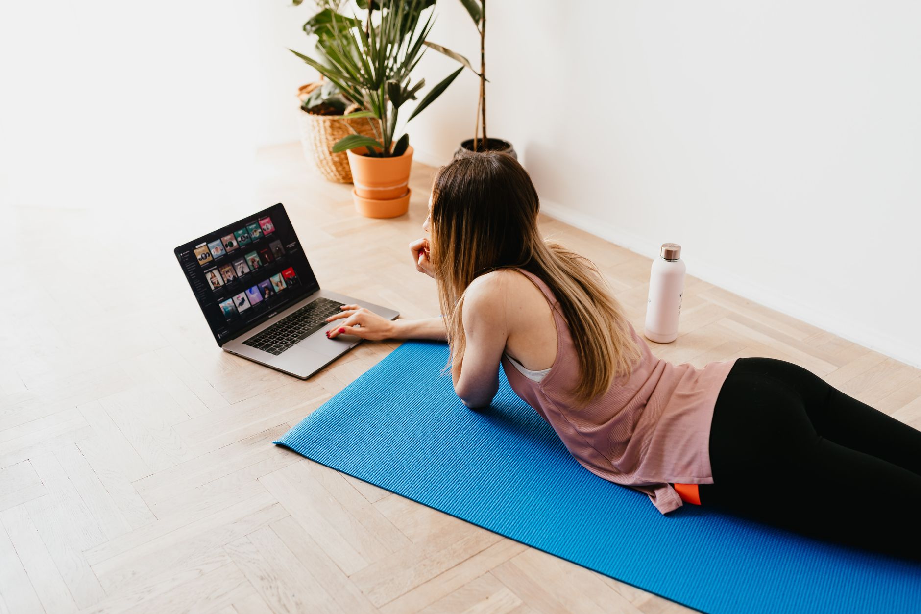 From above side view of young long haired female in casual wear lying on floor on blue mat while ... (Photo by www.kaboompics.com on Pexels)